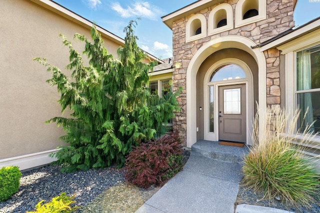 property entrance featuring stone siding and stucco siding