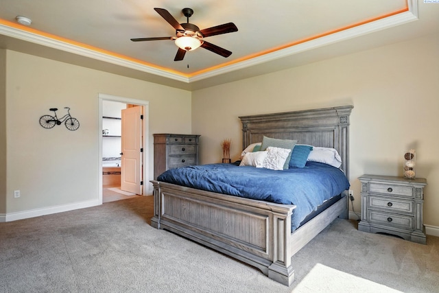 carpeted bedroom with a raised ceiling, ensuite bath, a ceiling fan, baseboards, and ornamental molding