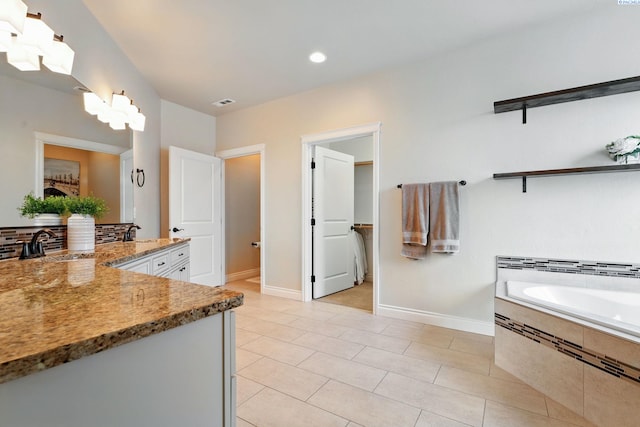 bathroom featuring visible vents, baseboards, a bath, tile patterned floors, and vanity