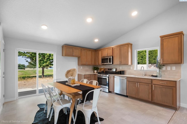 kitchen with high vaulted ceiling, stainless steel appliances, sink, and decorative backsplash