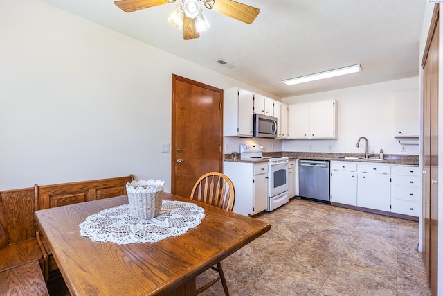 627 N Williams St, Kennewick, WA 99336 - kitchen featuring appliances with stainless steel finishes, dark countertops, white cabinetry, ceiling fan, and stone finish flooring