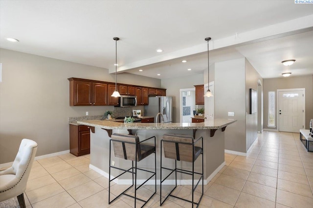 kitchen with light tile patterned floors, a kitchen bar, and stainless steel appliances