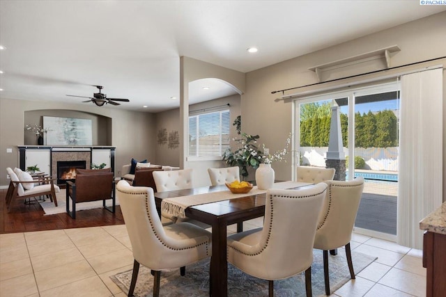 dining room with recessed lighting, light tile patterned flooring, ceiling fan, and a warm lit fireplace