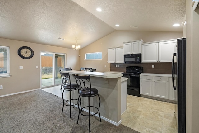 kitchen featuring pendant lighting, white cabinetry, a kitchen bar, black appliances, and a kitchen island