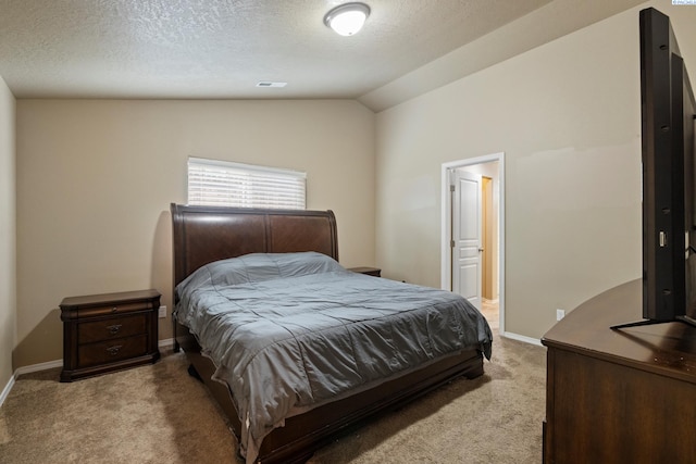 bedroom with lofted ceiling, light carpet, a textured ceiling, and ensuite bath