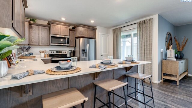 kitchen featuring sink, appliances with stainless steel finishes, dark hardwood / wood-style floors, a kitchen breakfast bar, and kitchen peninsula