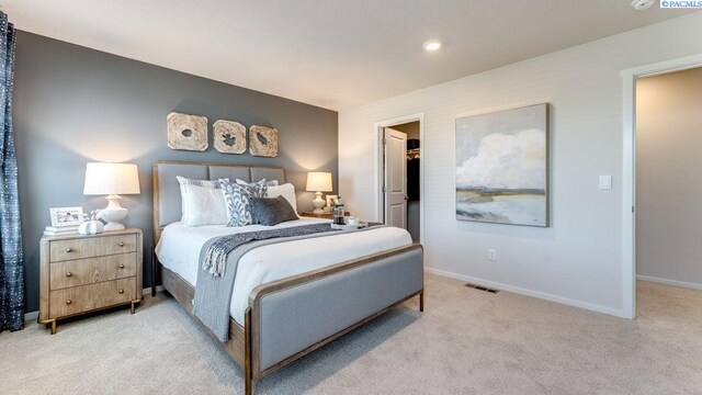 bedroom with light carpet, a spacious closet, and a closet