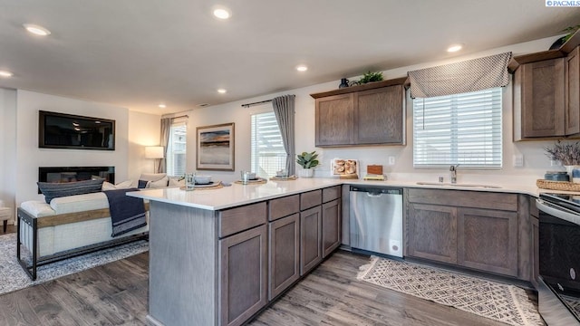 kitchen featuring stainless steel appliances, dark hardwood / wood-style floors, kitchen peninsula, and sink