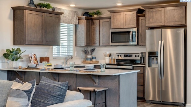 kitchen featuring sink, dark wood-type flooring, stainless steel appliances, and a kitchen breakfast bar