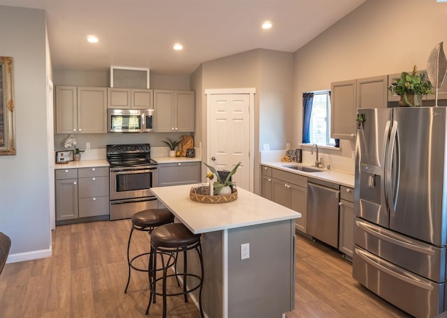 kitchen with gray cabinetry, sink, a kitchen island, and appliances with stainless steel finishes