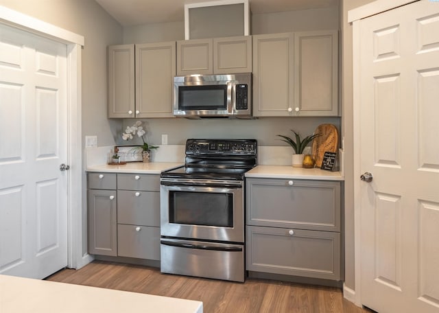 kitchen featuring appliances with stainless steel finishes, light hardwood / wood-style flooring, and gray cabinetry