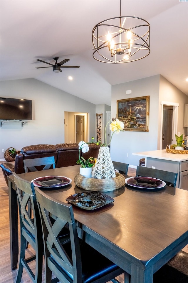 dining area featuring ceiling fan with notable chandelier, light hardwood / wood-style floors, and vaulted ceiling