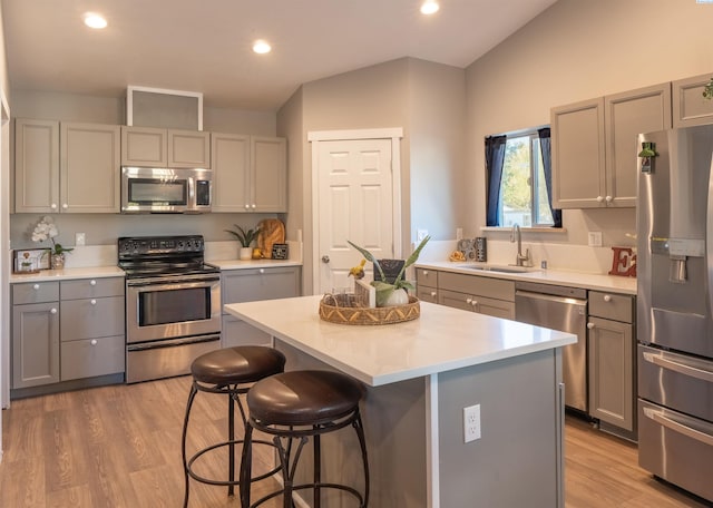 kitchen with sink, gray cabinets, appliances with stainless steel finishes, a center island, and light hardwood / wood-style floors