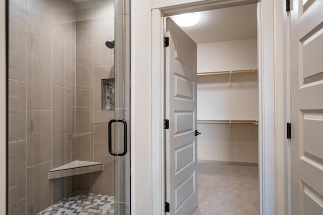 full bath featuring a stall shower, a spacious closet, and baseboards