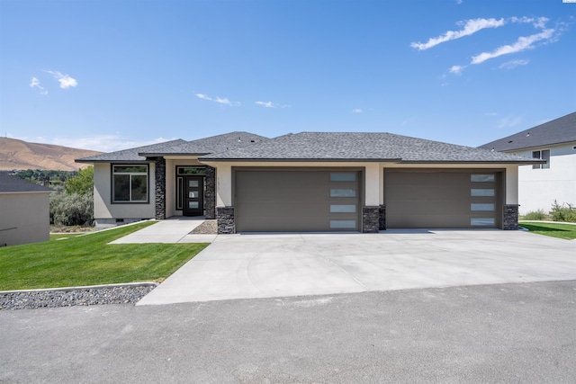 prairie-style home featuring a front lawn, a garage, and a mountain view