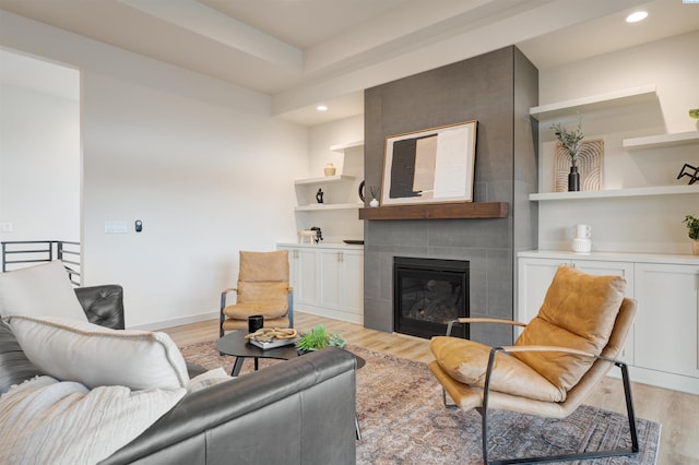 living room with light wood-style flooring, a fireplace, baseboards, and recessed lighting