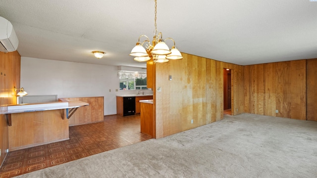 kitchen with an AC wall unit, brown cabinetry, wooden walls, dishwasher, and a notable chandelier