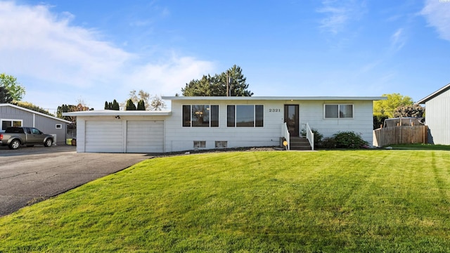 view of front facade featuring an attached garage, aphalt driveway, and a front yard