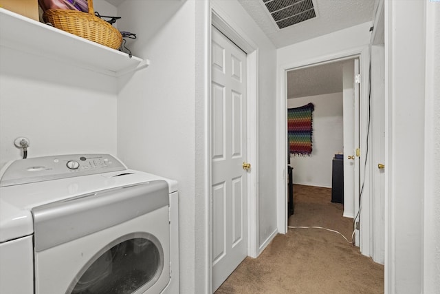 laundry room with light colored carpet, washer / dryer, and a textured ceiling