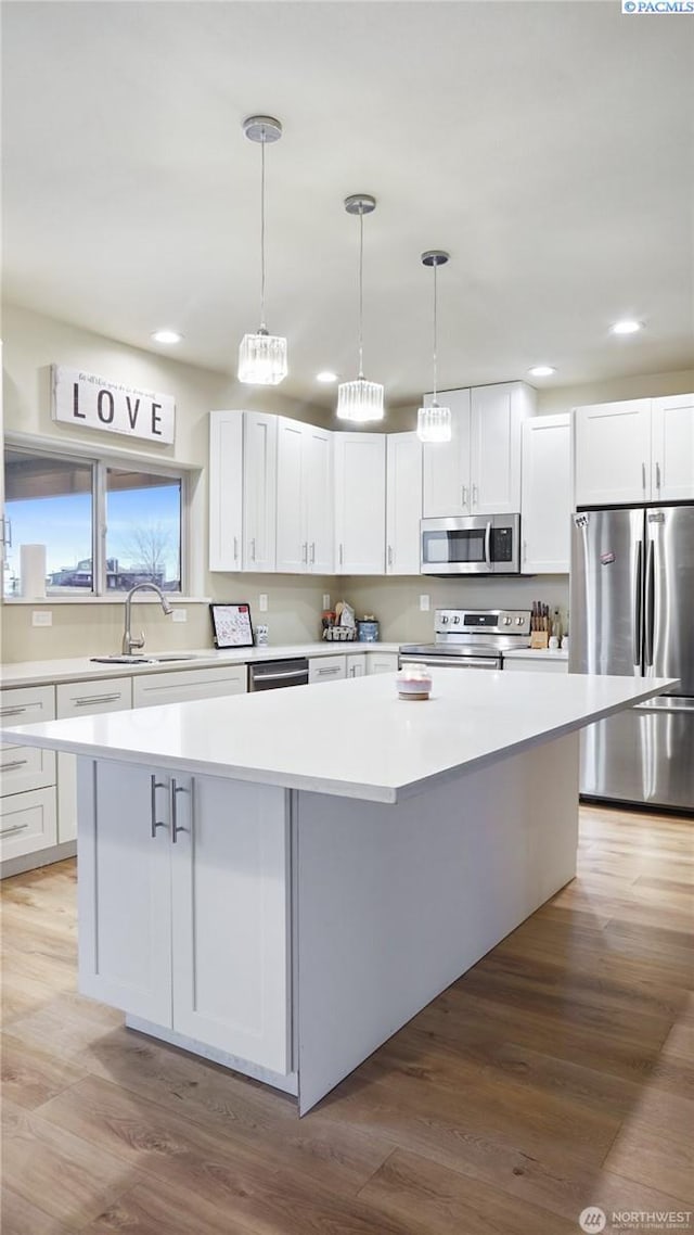 kitchen featuring white cabinetry, sink, stainless steel appliances, and a center island