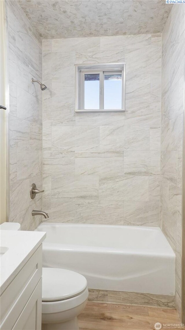 full bathroom with vanity, hardwood / wood-style flooring, tiled shower / bath combo, and toilet