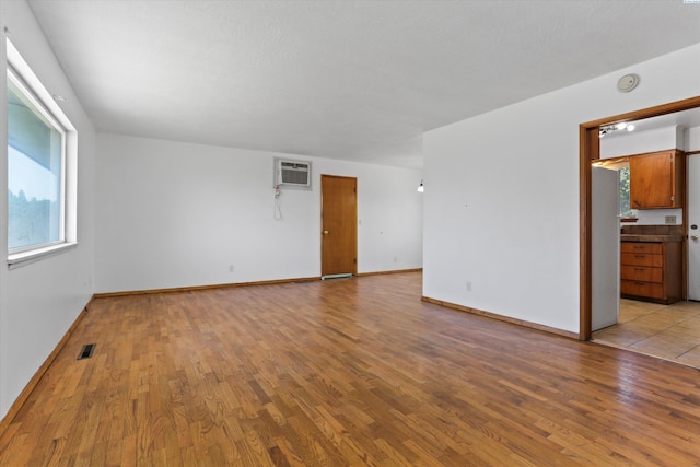 spare room featuring a wall mounted air conditioner and light hardwood / wood-style flooring