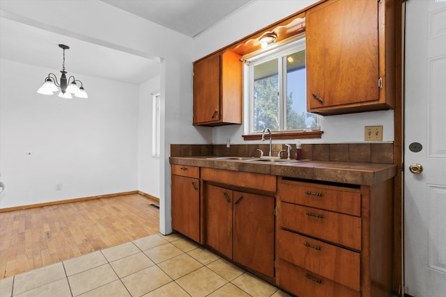 kitchen featuring a notable chandelier, decorative light fixtures, sink, and light tile patterned floors