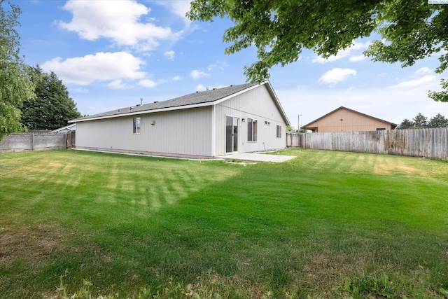 rear view of house featuring a lawn, a patio, and a fenced backyard