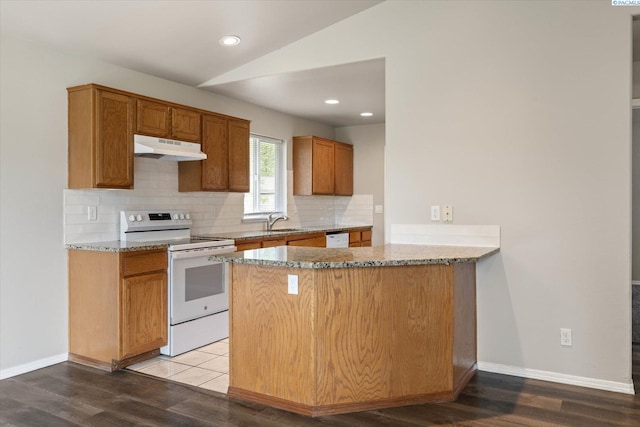 kitchen featuring tasteful backsplash, a sink, lofted ceiling, under cabinet range hood, and white appliances