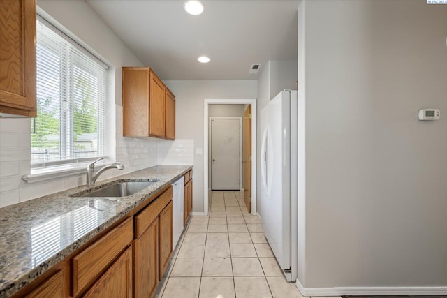 kitchen with decorative backsplash, visible vents, brown cabinets, a sink, and white appliances
