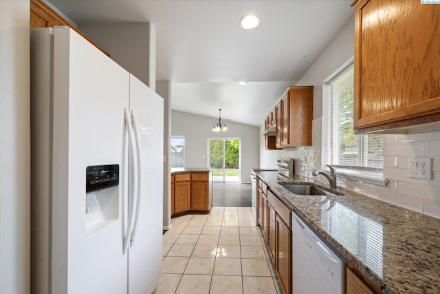 kitchen featuring a sink, white appliances, brown cabinetry, decorative backsplash, and lofted ceiling