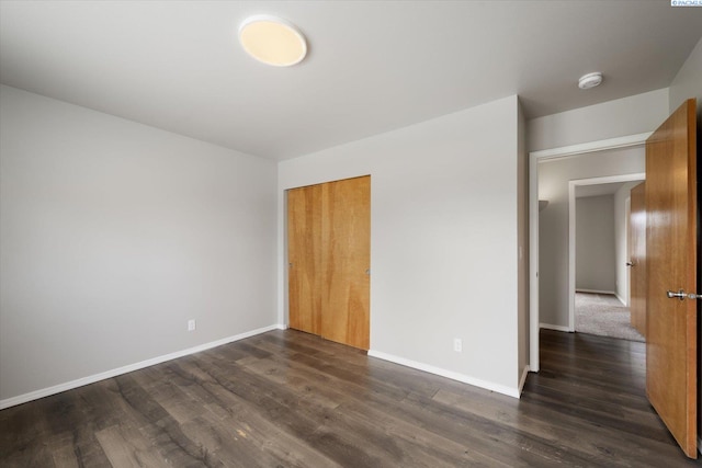 unfurnished bedroom with dark wood-type flooring, baseboards, and a closet