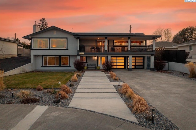 exterior space with an attached garage, a balcony, fence, driveway, and a yard