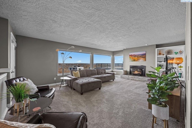 carpeted living area featuring baseboards, a textured ceiling, and a glass covered fireplace