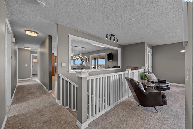 hallway with baseboards, carpet flooring, and an upstairs landing