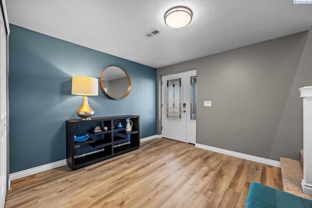 foyer featuring visible vents, baseboards, and wood finished floors