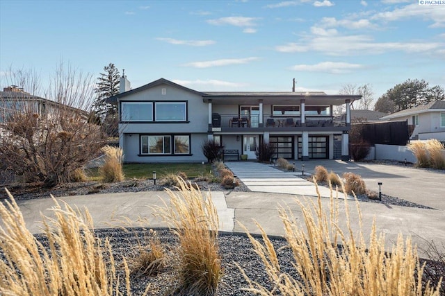 view of front of property featuring a garage, concrete driveway, a balcony, and stucco siding