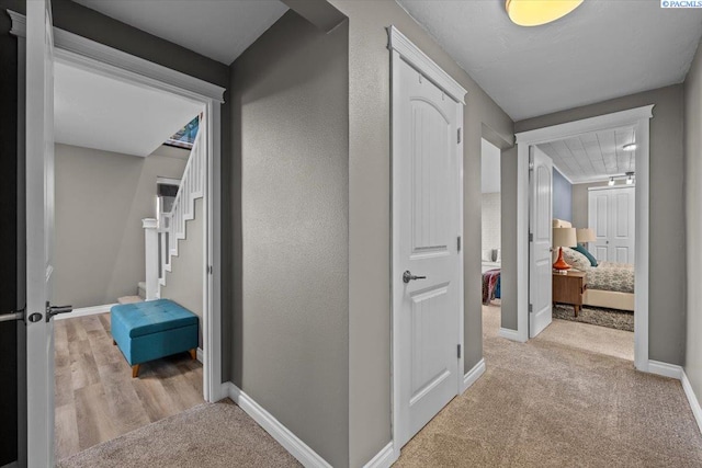 hallway featuring stairway, carpet flooring, and baseboards