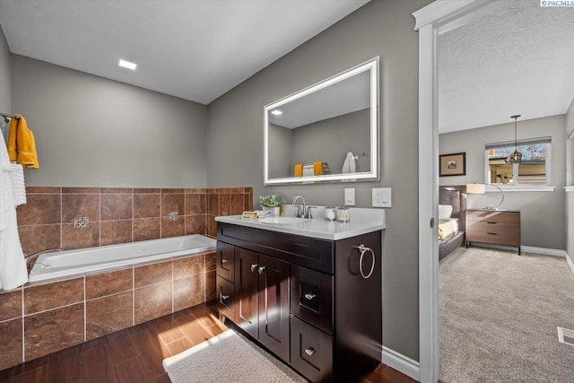 bathroom with a garden tub, visible vents, vanity, wood finished floors, and baseboards