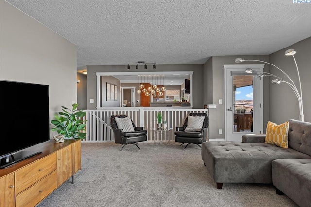 carpeted living room with a textured ceiling, track lighting, and a notable chandelier