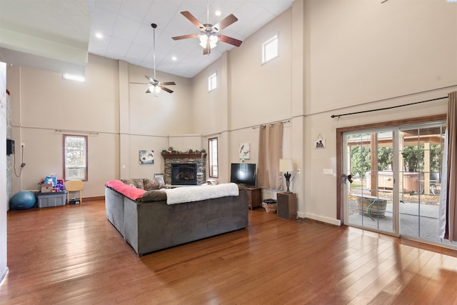 living room with wood-type flooring, ceiling fan, and a fireplace