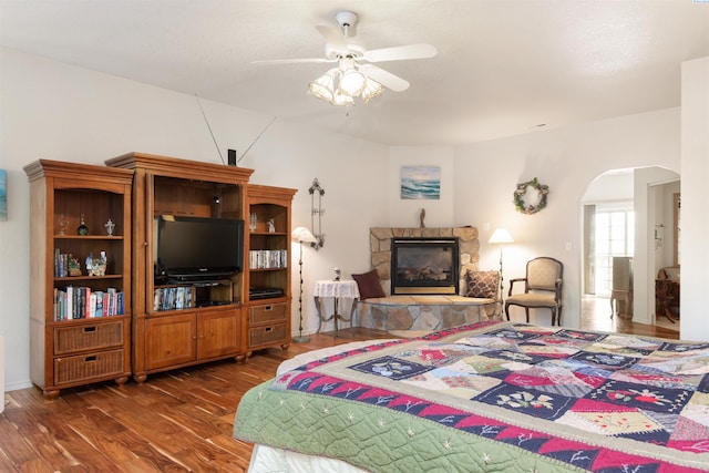 bedroom featuring ceiling fan, a fireplace, and dark hardwood / wood-style flooring