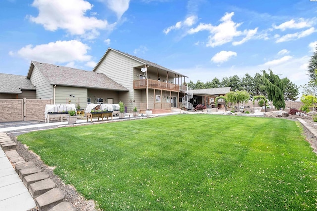 back of house featuring a patio, outdoor lounge area, a yard, and a balcony