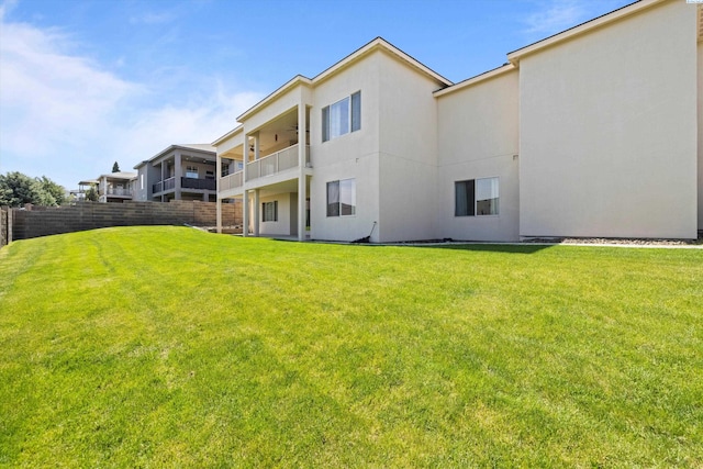 rear view of property with a lawn and a balcony