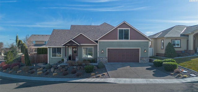 craftsman house featuring a garage, concrete driveway, stone siding, and fence