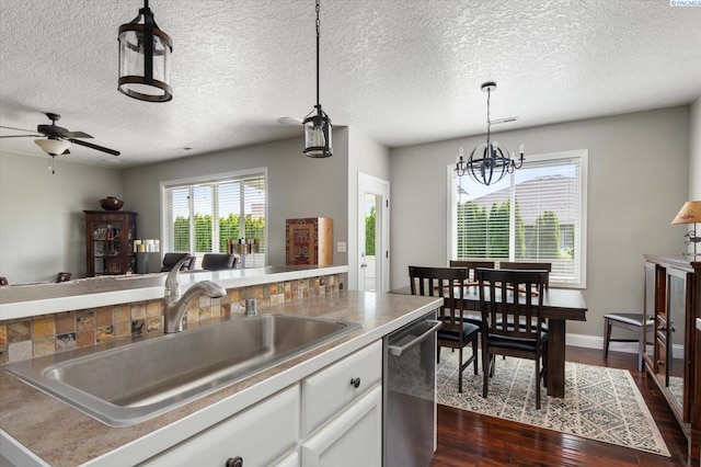 kitchen featuring sink, dark wood-type flooring, white cabinetry, decorative light fixtures, and stainless steel dishwasher