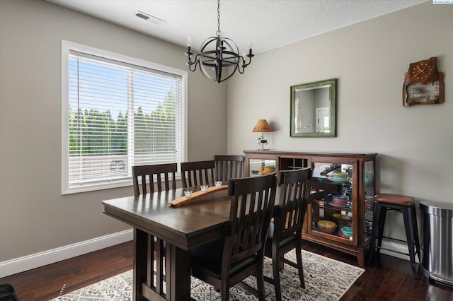 dining space with dark wood-type flooring, an inviting chandelier, and a textured ceiling