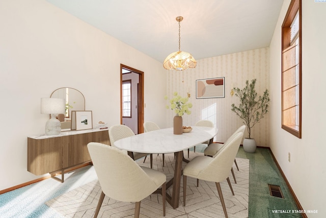 dining room with light colored carpet, visible vents, a chandelier, baseboards, and wallpapered walls