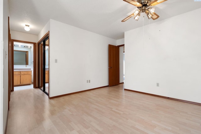 unfurnished room featuring a ceiling fan, light wood-style flooring, and baseboards