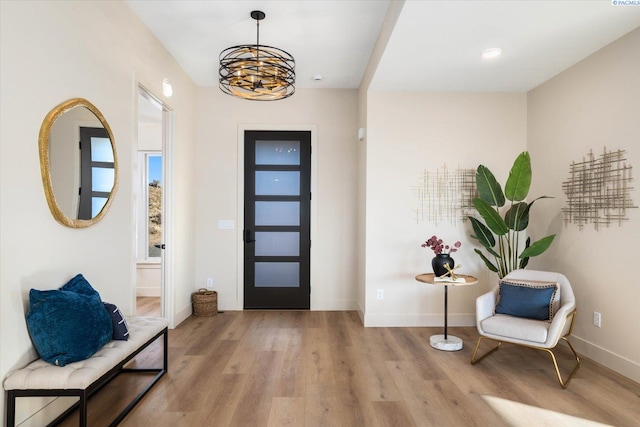 foyer entrance with light hardwood / wood-style floors and a chandelier